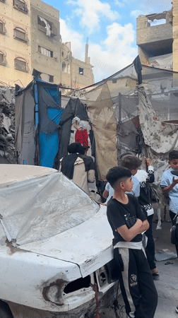 Children play on trampoline amid damaged buildings in Gaza