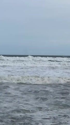 A time-lapse video shows the ocean and sky. The sky is overcast and a uniform gray. The ocean has multiple rows of waves, all appearing to be the same size. The waves are white-capped and rolling towards the viewer. The video begins at 00:00 and ends at 00:04.