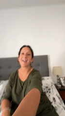Woman gestures and smiles on bed in San Isidro bedroom