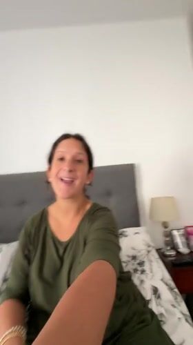 Woman gestures and smiles on bed in San Isidro bedroom