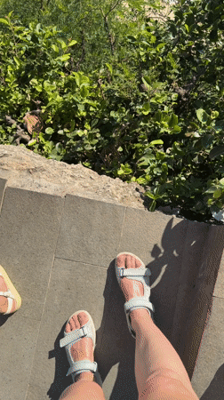 Two people in grey sandals filmed on stone tiles, Nusa Penida