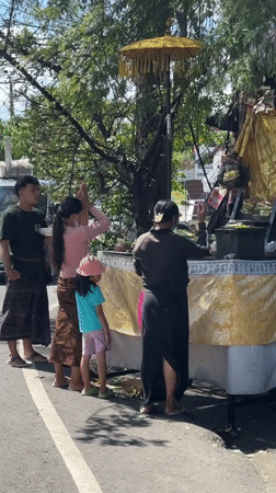 Family performs roadside religious ceremony in Denpasar Barat