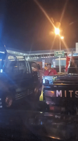 Vendors work a nighttime traffic queue at Melaya toll plaza