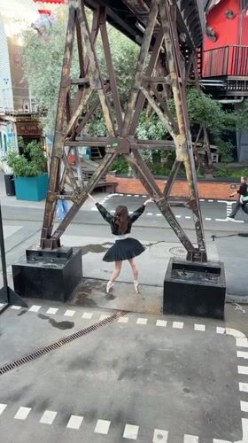 Ballerina in black tutu poses against rusty industrial structure in Moscow