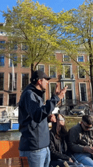 Canal tour group enjoys Amsterdam architecture commentary with orange leis