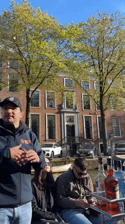 Canal tour group enjoys Amsterdam architecture commentary with orange leis