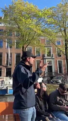 Canal tour group enjoys Amsterdam architecture commentary with orange leis
