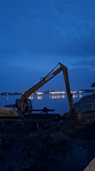 Excavator sits idle on waterfront in Lhokseumawe, Indonesia