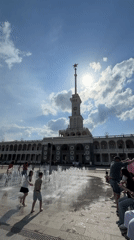 Children play in fountain outside clock tower building in Khimki