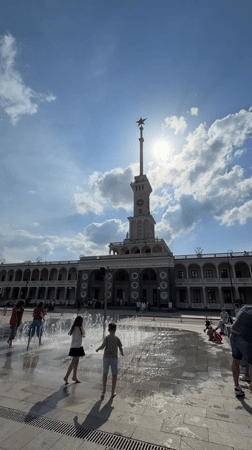 Children play in fountain outside clock tower building in Khimki