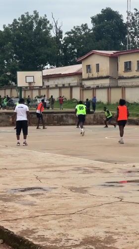 Outdoor basketball game on a wet concrete court in Jos, Nigeria