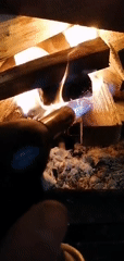 Person uses torch to light fireplace wood