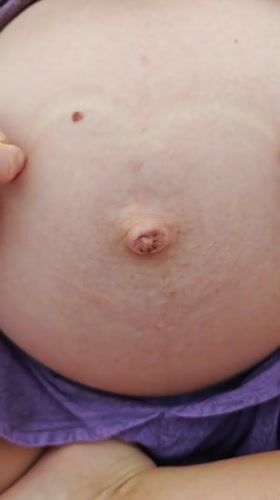 Pregnant person tenderly touches belly in Praia Grande, Brazil