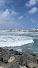 Waves crash against Las Palmas rocky coast under changing skies