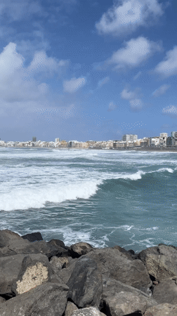 Waves crash against Las Palmas rocky coast under changing skies