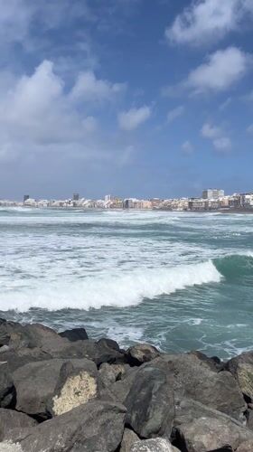 Waves crash against Las Palmas rocky coast under changing skies