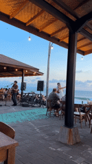 Beachside patio hosts live guitar performance during sunset hours