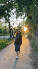 Woman walks tree-lined pathway in evening light, Kryvyi Rih