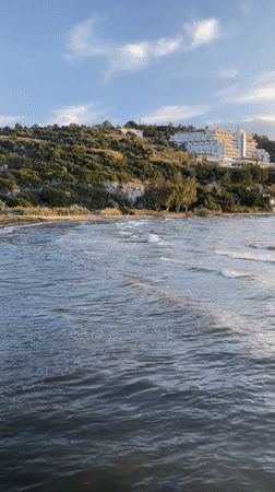 Coastal scene recorded in Selçuk, Turkey shows waves and beachgoers