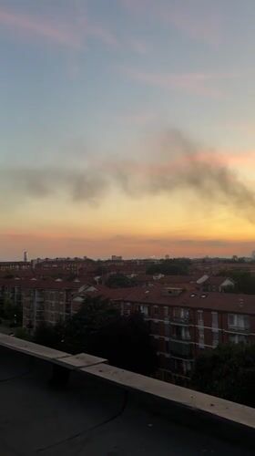Milan skyline at sunset, smoke drifting over the city