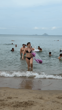 Busy morning at Nha Trang beach features swimmers, vendors, mermaid performers