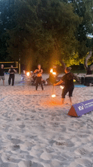 Fire performers demonstrate skills on Saarbrücken beach during twilight