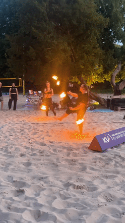 Fire performers demonstrate skills on Saarbrücken beach during twilight