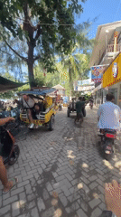 Moped rider navigates brick street in tropical Indonesia