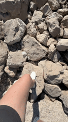 Person walks rocky beach in Bar, Montenegro on sunny afternoon