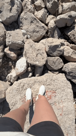 Person walks rocky beach in Bar, Montenegro on sunny afternoon