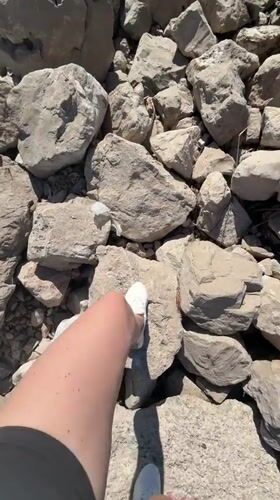 Person walks rocky beach in Bar, Montenegro on sunny afternoon