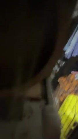 The video begins with a close-up of a chinchilla cage. A chinchilla is visible inside, and a hand reaches into the cage to pet it. The chinchilla appears to be dark grey with light grey markings, and it has large ears and a bushy tail. The cage is made of metal bars and has a hammock hanging inside. The lighting is dim, suggesting it might be nighttime or indoors with the lights off. The environment appears to be domestic, likely a home. The interaction between the hand and the chinchilla seems gentle and caring, indicating a positive emotional tone. There is no visible text in the video. The setting is identified as Demikhovo, Russia.