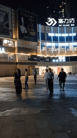 Women square dancing in Chongqing plaza interrupted by scooter