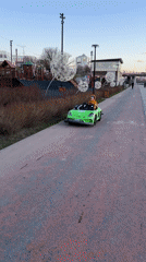Child drives toy car along Cheboksary waterfront path