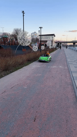 Child drives toy car along Cheboksary waterfront path