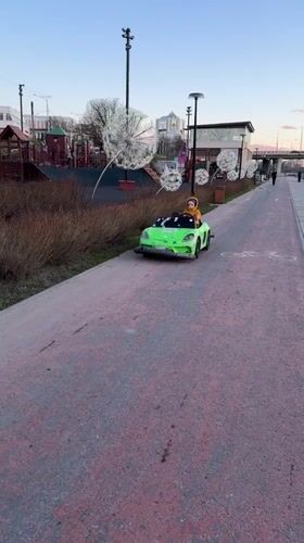 Child drives toy car along Cheboksary waterfront path