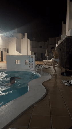 Boys swim and dive in nighttime pool in Teguise
