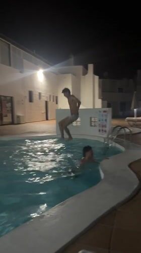Boys swim and dive in nighttime pool in Teguise