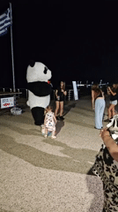 Panda mascot mingles with crowds in a Greek town square at night