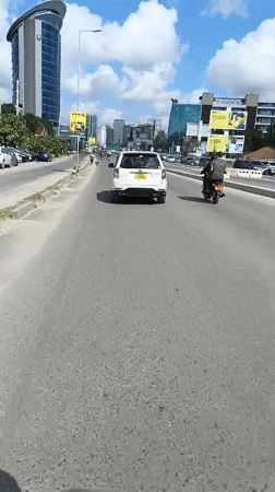 Motorcycle rider films sunny street scene in Dar es Salaam