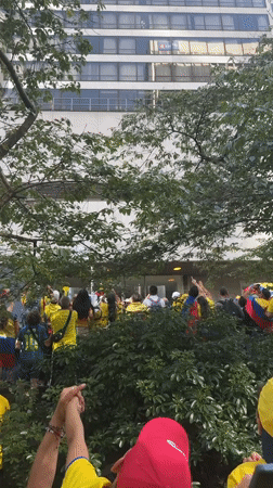 Yellow-shirted crowd rallies outside Vancouver building with flags raised