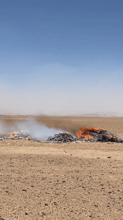 Burning debris piles in arid desert outside Mandisar, Afghanistan