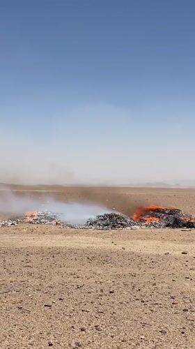 Burning debris piles in arid desert outside Mandisar, Afghanistan