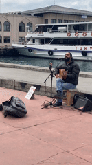 Street musician performs waterfront in Kadıköy amid daily neighborhood activity