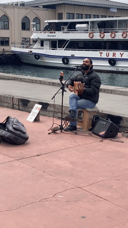 Street musician performs waterfront in Kadıköy amid daily neighborhood activity
