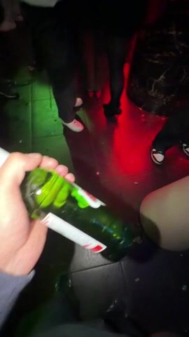 Here is a description of the video.
The video shows a person holding a bottle of Stella Artois beer at a club. The club has multiple people socializing and dancing with electronic music in the background. People are standing and sitting at tables. The club has colored lighting on the ceiling and walls.