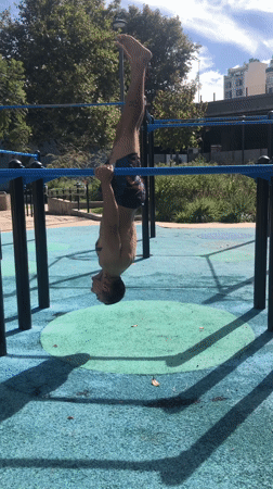 Man performs upside-down exercise on parallel bars in Buenos Aires park
