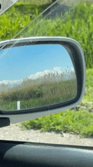 Driver captures Kyrgyzstan countryside through car mirror while traveling