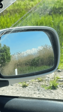 Driver captures Kyrgyzstan countryside through car mirror while traveling