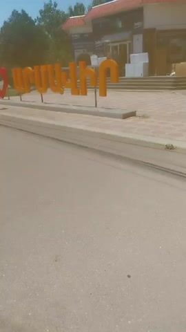 The video shows a street scene with an "I love" sign featuring Armenian letters. In the background, a store with a "beko" sign is visible. The weather appears to be sunny.